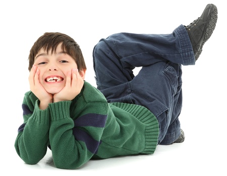 Adorable and very flexible 7 year old french american boy laying on belly with legs twisted behind him.  Smiling.の写真素材