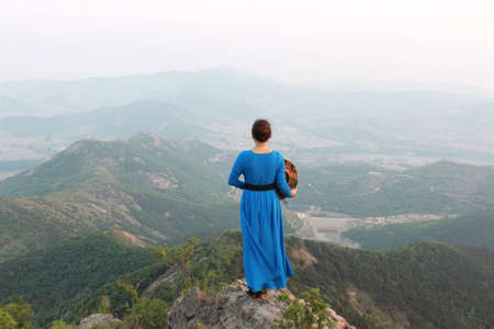 blue dress woman standing at the top of mountainの写真素材