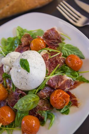 Salad with tomatoes, ruccola, Burrata and jamon ibericoの写真素材
