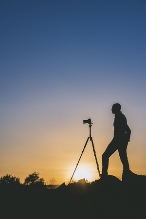 Silhouette of black photographer taking pictures at sunset. Image with copy space.の写真素材