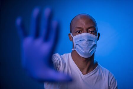 STOP Coronavirus, African American man shows the stop coronavirus sign, wearing protective mask and...