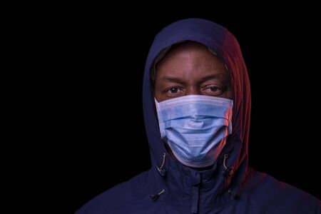 Coronavirus, African American man with protective mask, looking at the camera. COVID-19 concept. Studio shot on black background with copyspace.の写真素材