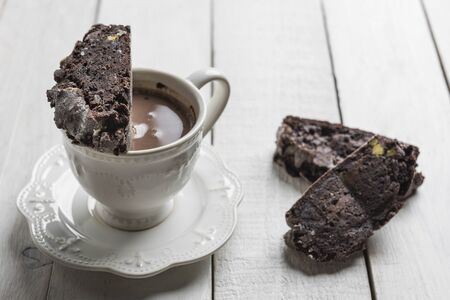 Chocolate Biscotti or Cantuccini over a cup of chocolate, on a white wooden table.の写真素材