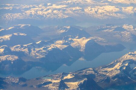 Mountains reflecting in frozen lakes near the coast of Greenland.の写真素材