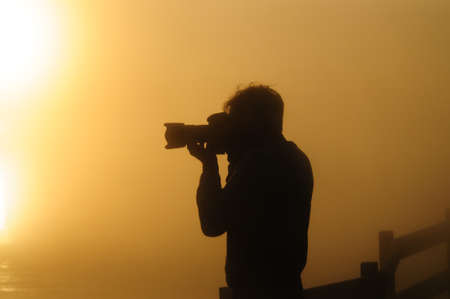 Silhoutte of a photographer shooting a sunrise in the West Thumb Area in Yellowstone National Park.の写真素材