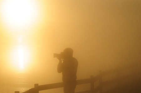 Silhoutte of a photographer shooting a sunrise in the West Thumb Area in Yellowstone National Park.の写真素材