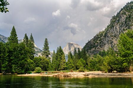A rare July Thunderstorm building up over the Sierra Nevada Mountain range, seen here across the Merced river and Half dome, in Yosemite National Park.の写真素材