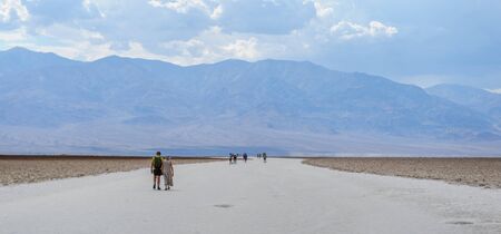 A scattered group of tourists walking down the salt flats near the Badwater area in Death Valley National Park, USA.の写真素材