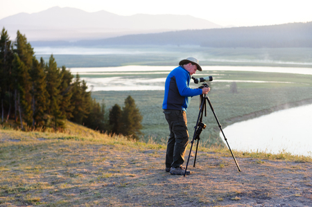 Hayden Valley, WY, July 14, 2016. An animal watcher setting up binoculars and tripod in Hayden Valley, Yellowstone National Park. Hayden Valley is a popular spot for watching bisons and Grizzly Bears.のeditorial素材