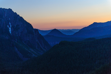 The Setting sun illuminates an orange-reddish night sky in mount Rainier National Parkの写真素材