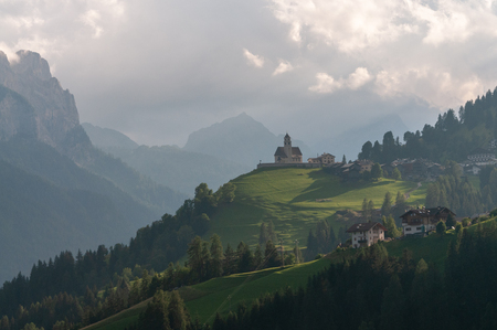 The Church in the village of Colle Santa Lucia in the Golden hours, just before sunset. Italian Dolomites on a summers evening.の写真素材