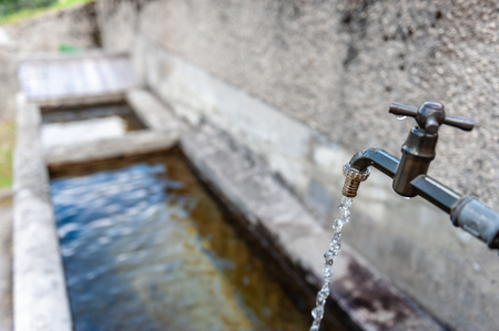 A tap from a drinking water fountain in the village of Santa Fosca, in the Italian Dolomites on a Summer morning.の写真素材