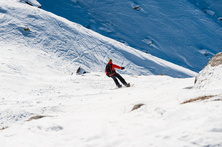 Chamonix de Mont Blanc, France, December 24, 2015. A snowboarder wearing a bright red vest descending from the Plan de lAiguille towards Chamonix. The chamonix area is well known for outdoor sports.の写真素材