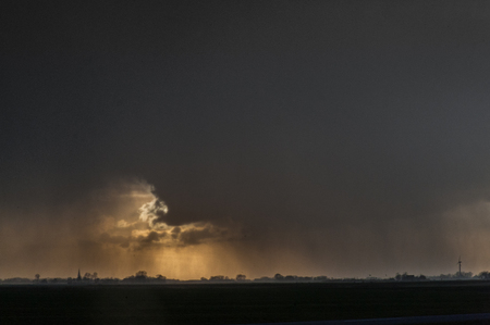 Imposing storm clouds gathering over the Northern Parts of Friesland, the Netherlads, during sunsetの写真素材