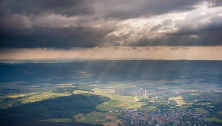 Rays of Sunlight being caught through scattered rain showers over central Germany, as seen from the air, just before sunset.の写真素材