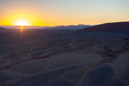 The rising sun illuminating the mighty dunes of the sossusvlei, as seen from dune 45, in Nambia.の写真素材