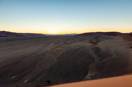 The rising sun illuminating the mighty dunes of the sossusvlei, as seen from dune 45, in Nambia.の写真素材