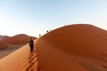 The rising sun illuminating the mighty dunes of the sossusvlei, as seen from dune 45, in Nambia.の写真素材