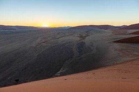 The rising sun illuminating the mighty dunes of the sossusvlei, as seen from dune 45, in Nambia.の写真素材