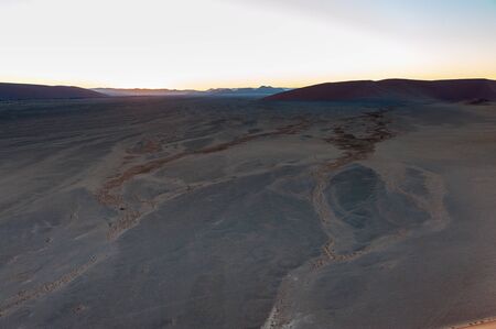 The rising sun illuminating the mighty dunes of the sossusvlei, as seen from dune 45, in Nambia.の写真素材