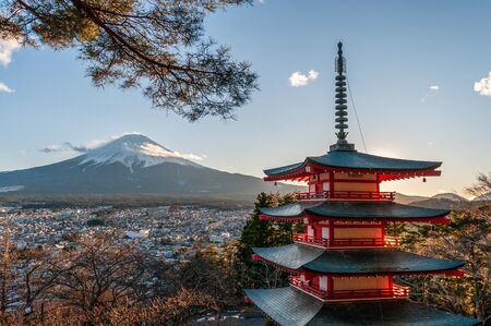 The last rays of the setting sun illuminating mount Fuji and the Churito Pagode on a December winter afternoon.の写真素材