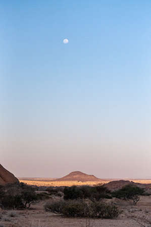 Shot of the moon over the namibian desert, near Spitskoppe, around sunset.の写真素材