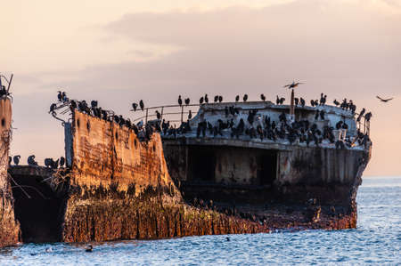 A beautiful sunset over the beach near Aptos, California, highlighting the old derelict pier and an old shipwreck.の写真素材