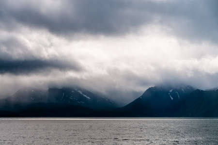 Low hanging clouds contrast with mountains and lakes in northern norway.
