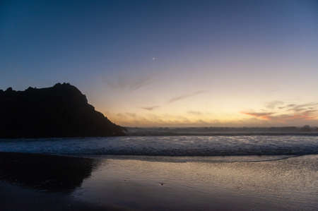 Rocks in the surf of Pfeiffer beach, around sunset. Deep yellow orange clouds color the sky.の写真素材