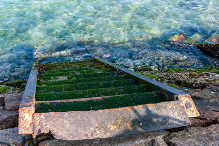 An old rusty staircase leading to the ocean on Japans shiraishi island.