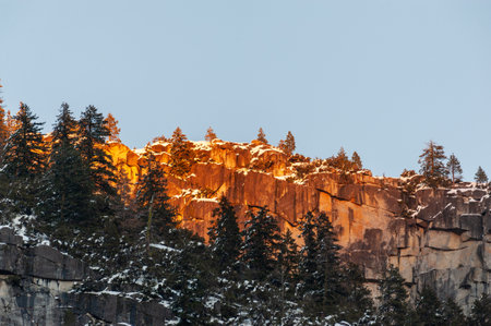Illuminated mountain top on a wintery afternoon in Yosemite national park, catching the last rays of...