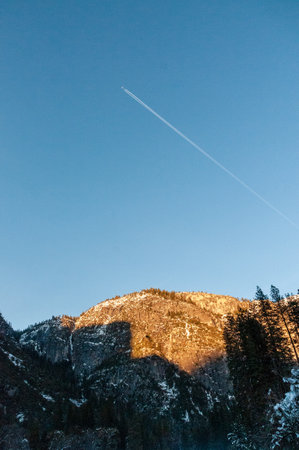 Exterior shot of an airliner passing overhead Yosemite national park on a late winter afternoon, just before sunset.の写真素材