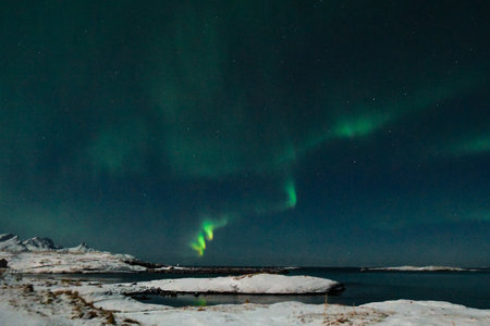 Bright Green Colours of the Northern Light, Aurora Borealis illuminate the Night Sky over the beach...