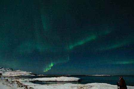Bright Green Colours of the Northern Light, Aurora Borealis illuminate the Night Sky over the beach at Mjelle, in Arctic Norway.の写真素材