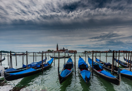 Venice, Italy. June 20, 2015. Gondolas moored along the Riva degli Schiavoni. Featuring the Chiesa di San Giorgio Marggiore in the Background.のeditorial素材