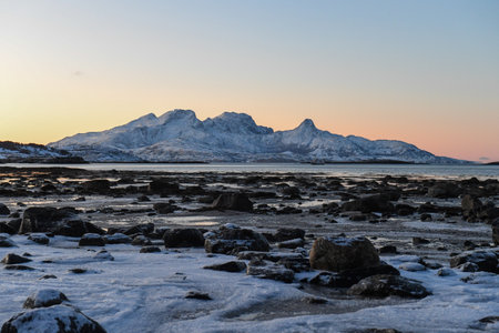 Wide angle landscape shot of the snow covered mountains and beach near Mjelle, part of the Bodo...