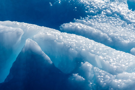 Detail of a patch of Antarctic sea ice, containing wonderous shapes and deep blue colours.