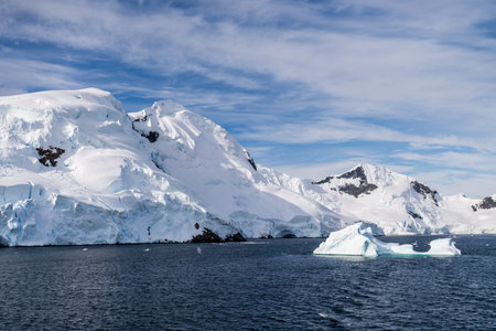 A tranquil Antarctic landscape, near Graham passage along Charlotte Bay, highlighting stark reflections, rugged mountains, and impressive icebergs.の写真素材