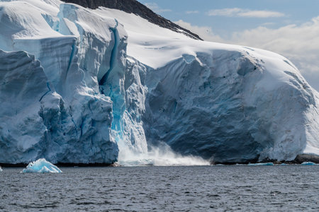 Telephoto of a giant chunk of ice calving off an ice sheet. Graham Passage, near Charlotte Bay, on the Antarctic Peninsulaの写真素材