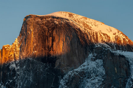 Telephoto shot of a snowy half dome catching the last rays of sunlight on a winter evening.の写真素材