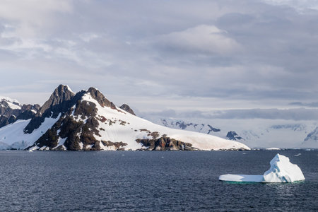 A tranquil Antarctic landscape, near Graham passage along Charlotte Bay, highlighting stark reflections, rugged mountains, and impressive icebergs.の写真素材