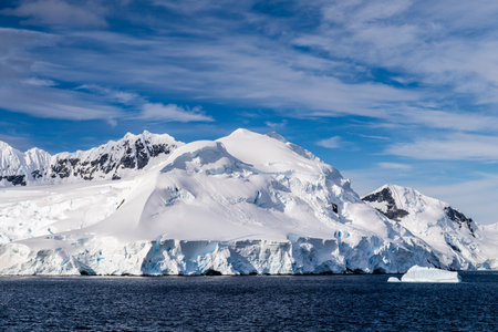 A tranquil Antarctic landscape, near Graham passage along Charlotte Bay, highlighting stark reflections, rugged mountains, and impressive icebergs.の写真素材