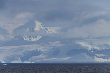 A tranquil Antarctic landscape, near Graham passage along Charlotte Bay, highlighting stark reflections, rugged mountains, and impressive icebergs.の写真素材