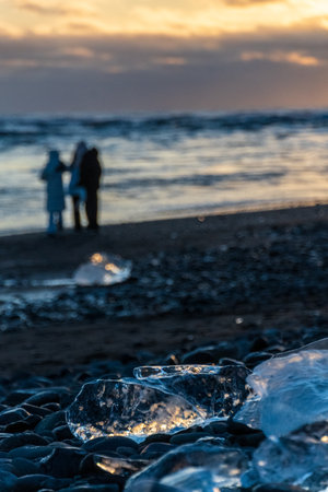 Beatiful, golden hour sunlight is refracted in melting ice on diamond beach, near Jokulsarlon...