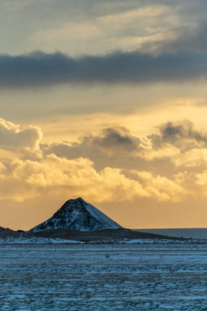 A beautiful snowy winter landscape from southern Iceland, basking in the beautulf soft pink light of a low hanging sun. Winterdays in Iceland are marked by a perpetual golden hour.の写真素材