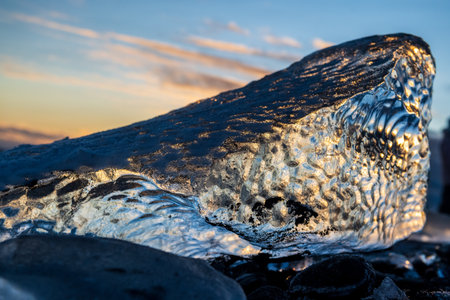 Beatiful, golden hour sunlight is refracted in melting ice on diamond beach, near Jokulsarlon...