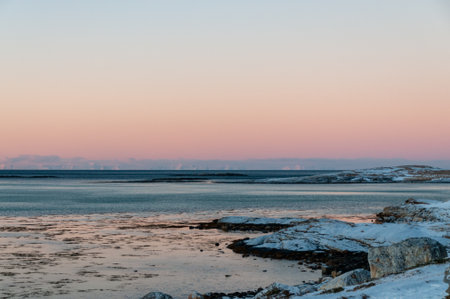 Landscape shot highlighting the rugged mountains and snow-covered beaches of arctic norway during a brief golden hour during the long winters.の写真素材