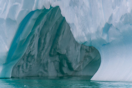 An Antarctic landscape shot near Cuverville island, highlighting mountains and icebergs.