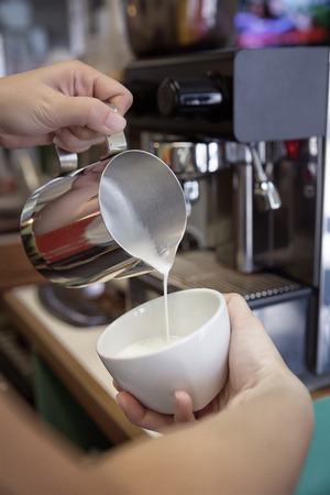 Barista making cappuccino in his coffeeshop or cafe, close-upの写真素材