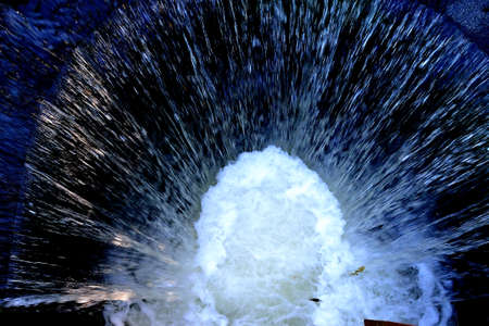 Photograph of a water storm created by breaking waves in the culvert of a flooded streamの写真素材